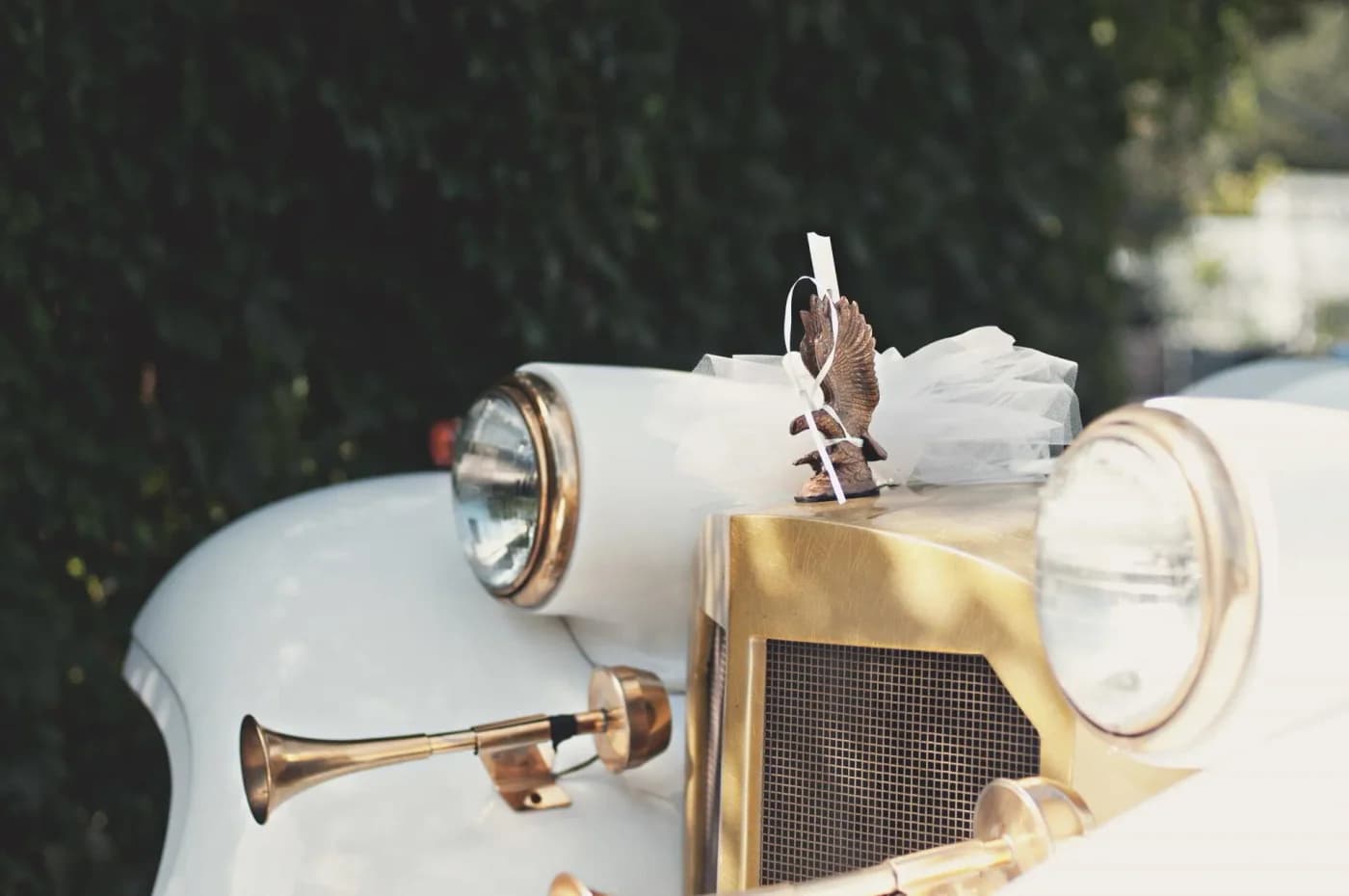 Cream vintage wedding car with a white tulle decoration