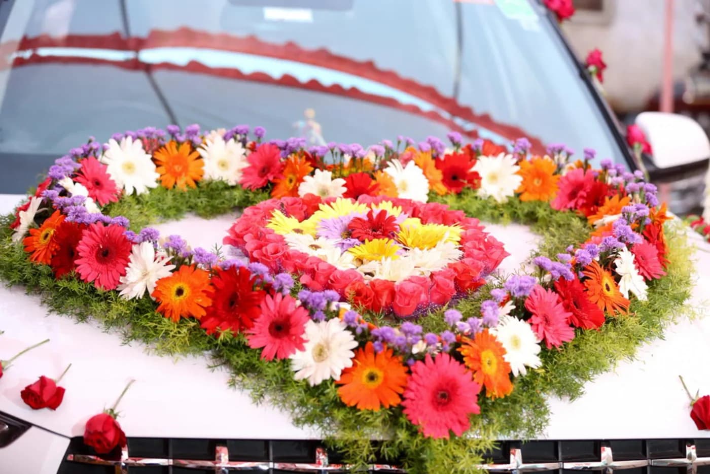 Red wedding car decorated with a heart of colourful flowers