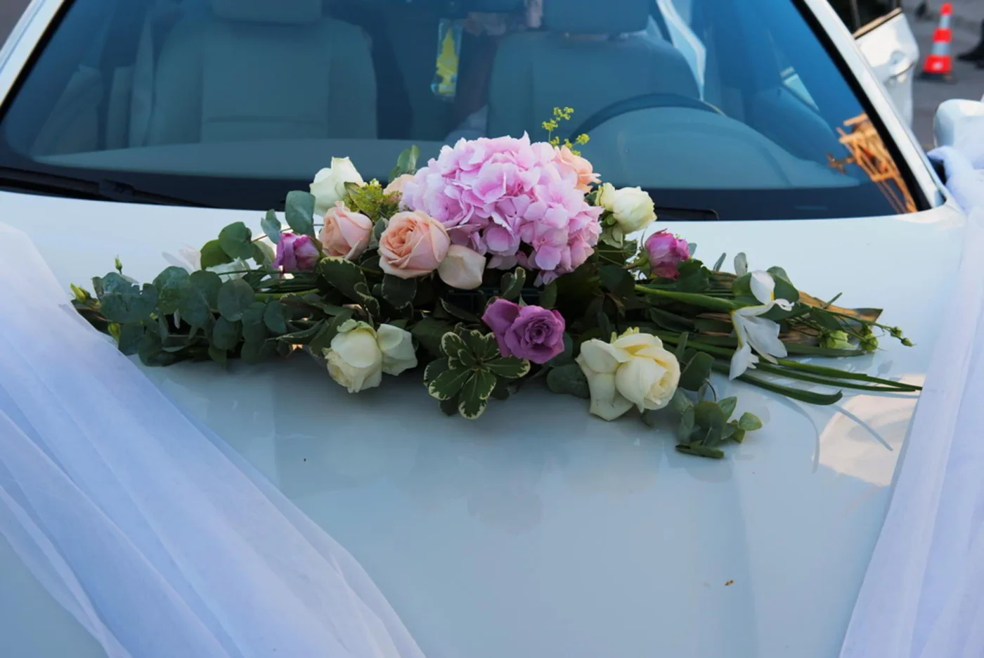 Pink roses and greenery on a white wedding car bonnet