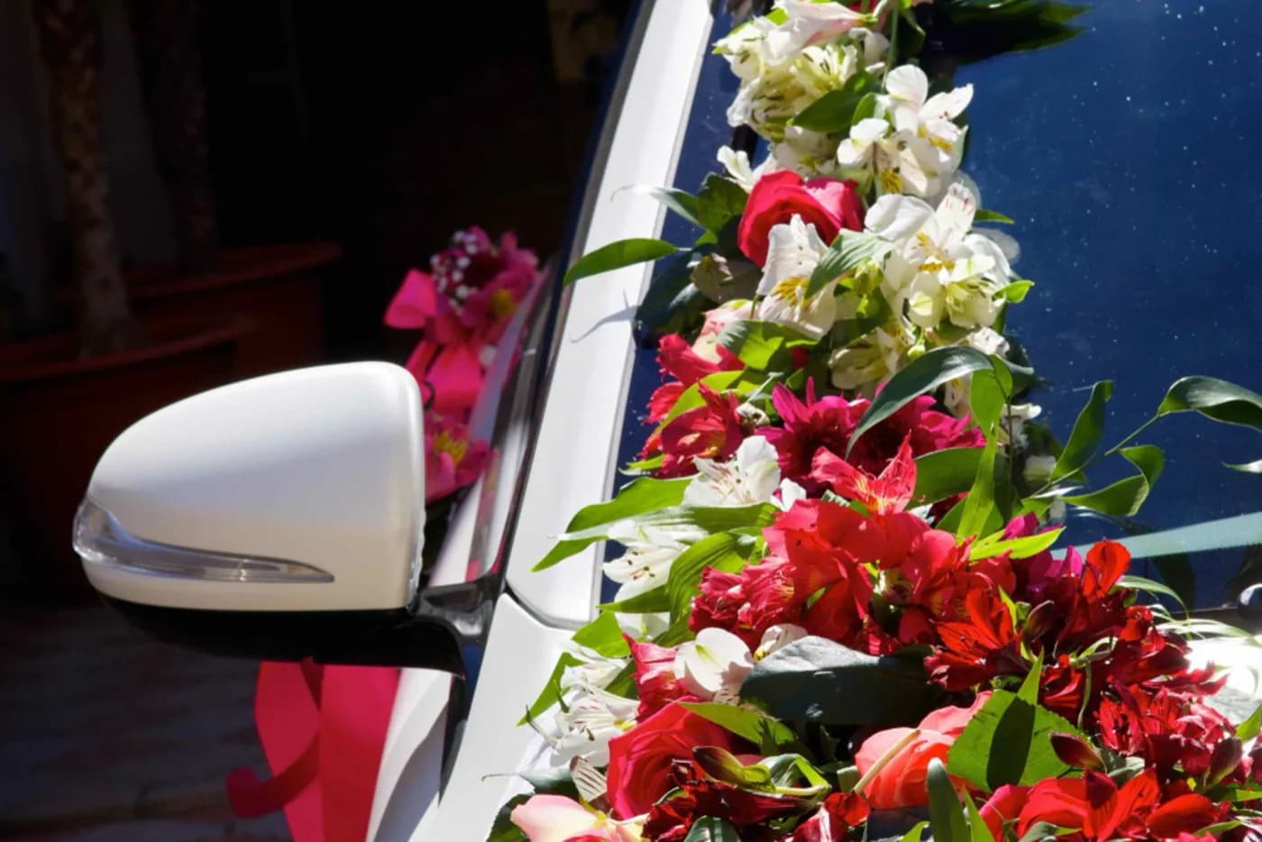Colourful flowers arranged beside a white wedding car windscreen