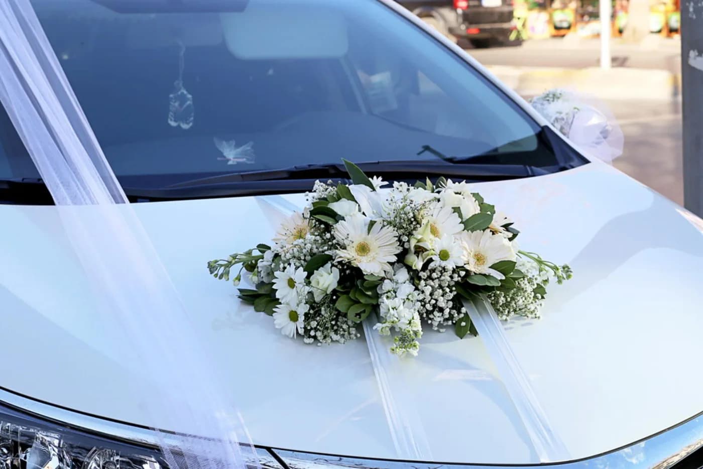 White wedding car with a white floral bouquet on its bonnet