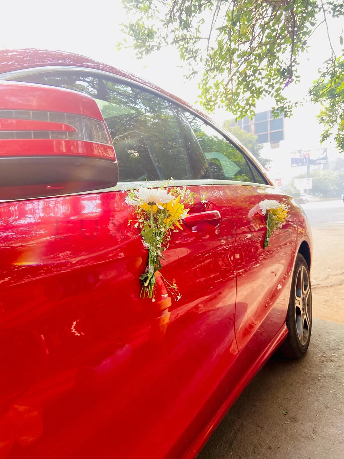 Wedding flowers tied to the mirror of a red Mercedes-Benz CLA