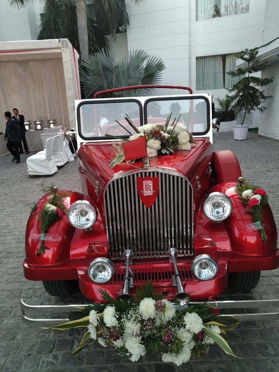Front view of a red vintage wedding car with white flowers