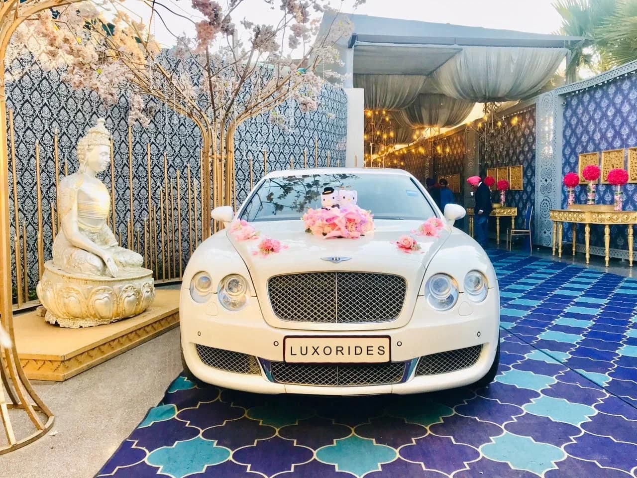 White Bentley with pink floral decorations at a wedding venue