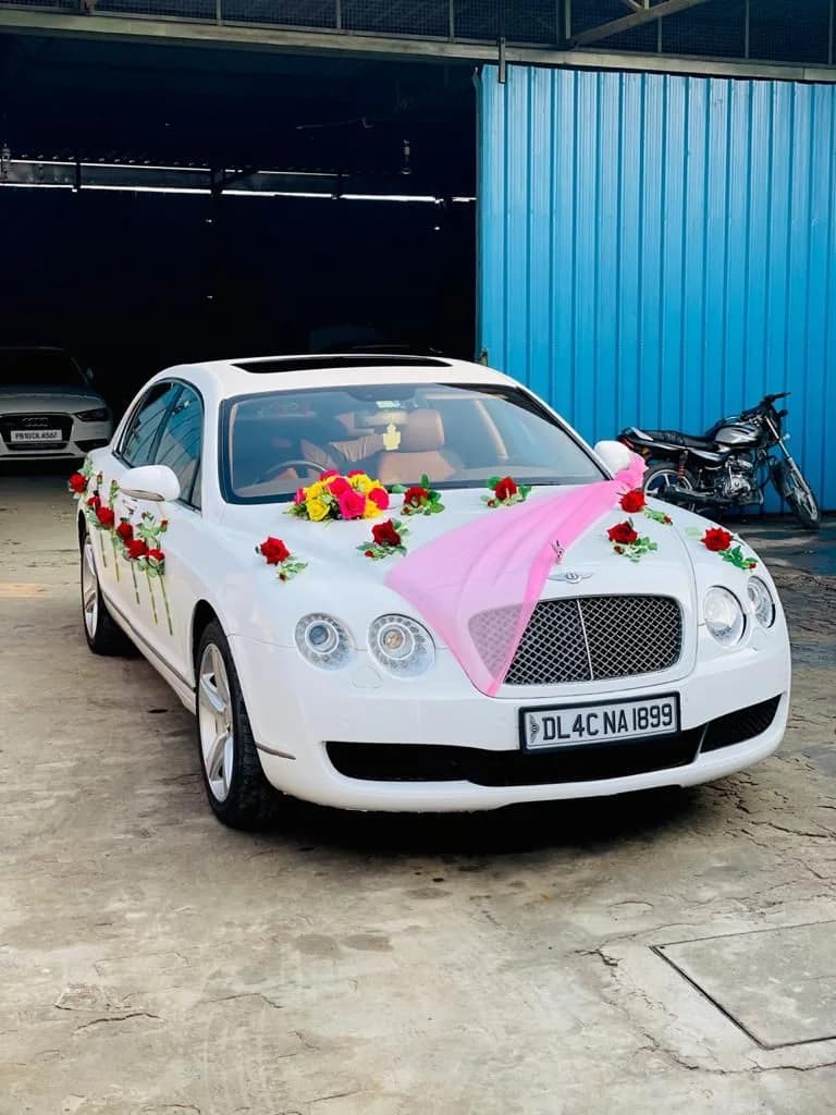 White Bentley wedding car styled with pink fabric and red roses