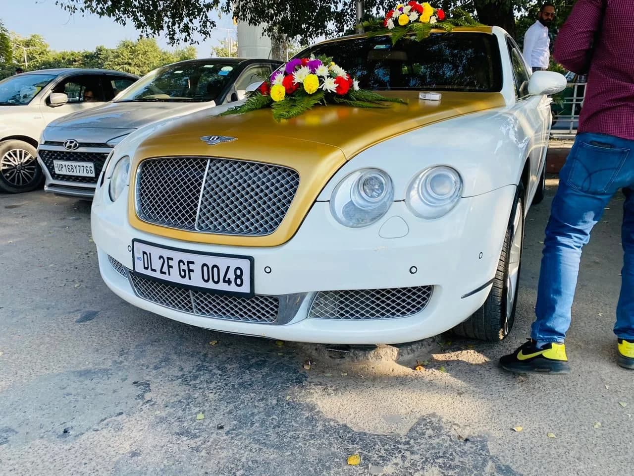 White and gold Bentley decorated with colourful wedding flowers