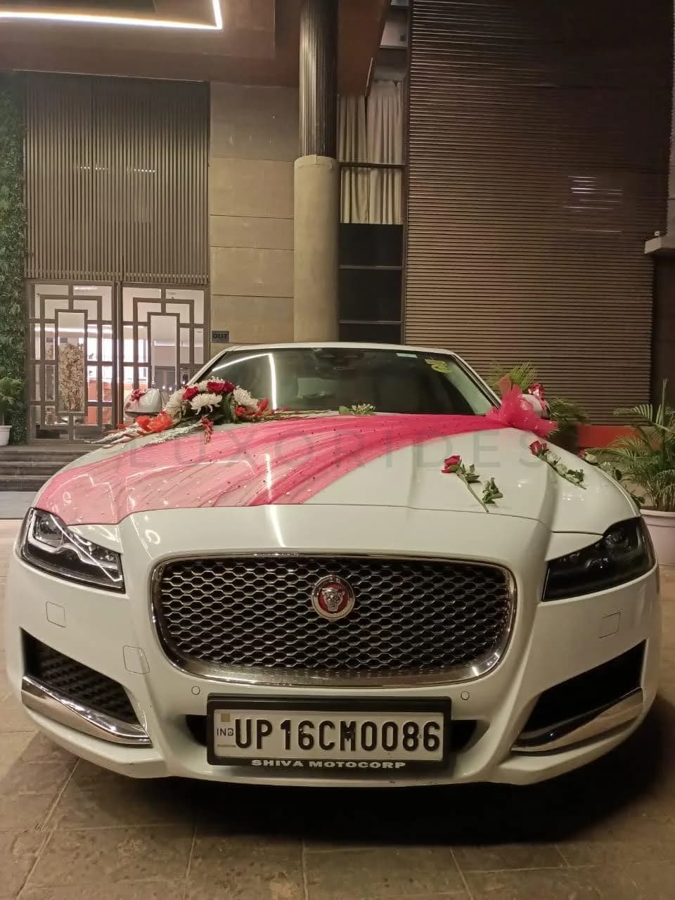 Front view of a white Jaguar XF with pink fabric and roses at night