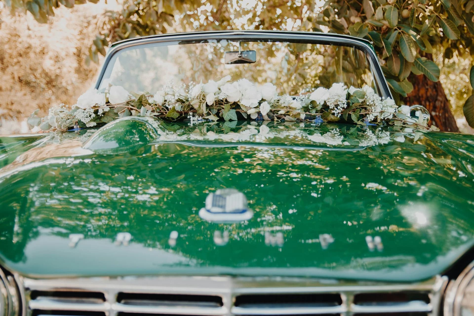 Green wedding car decorated with white flowers